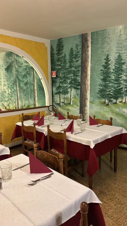 a restaurant with tables with red napkins and a large window at Hotel Europa in San Martino di Castrozza