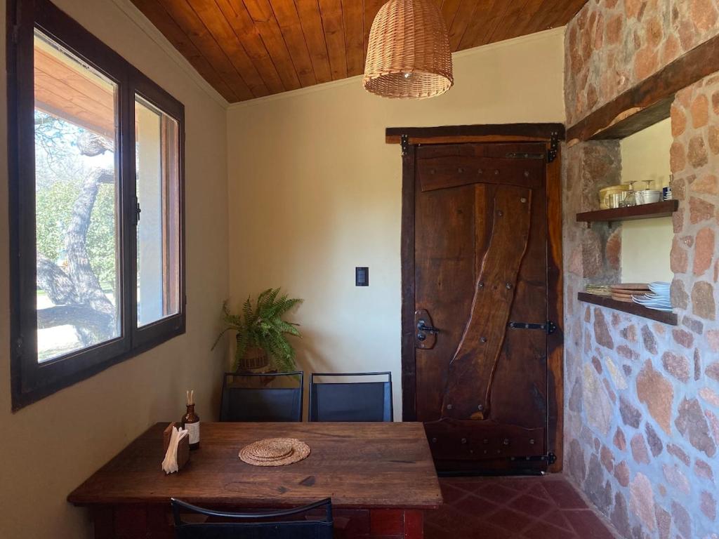 a room with a wooden table and a wooden door at Puesto de Montaña - Casa con pileta privada in Los Hornillos
