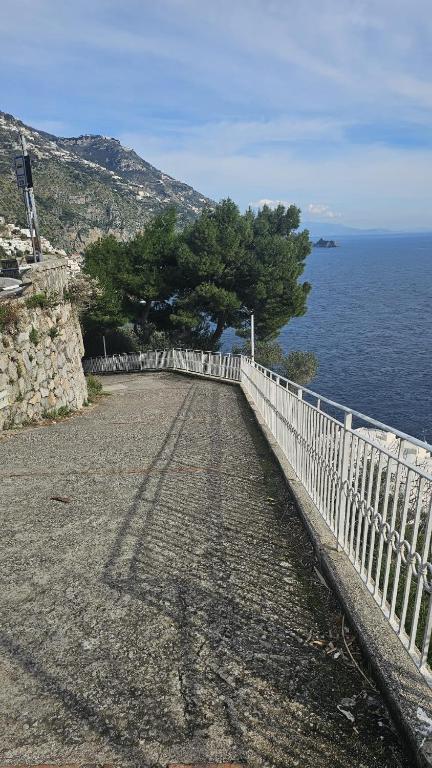 a white fence on a road next to the ocean at Casa La Scogliera in Praiano
