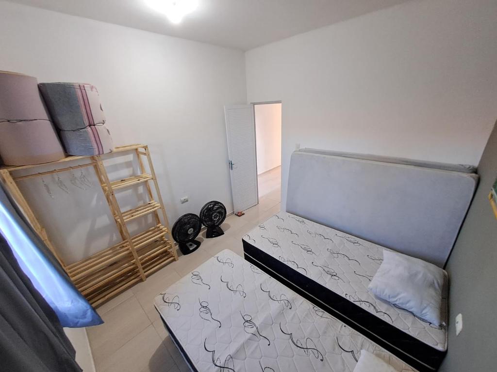 Una pequeña habitación con una cama y un estante. en Tô em casa Tamandaré, en Tamandaré