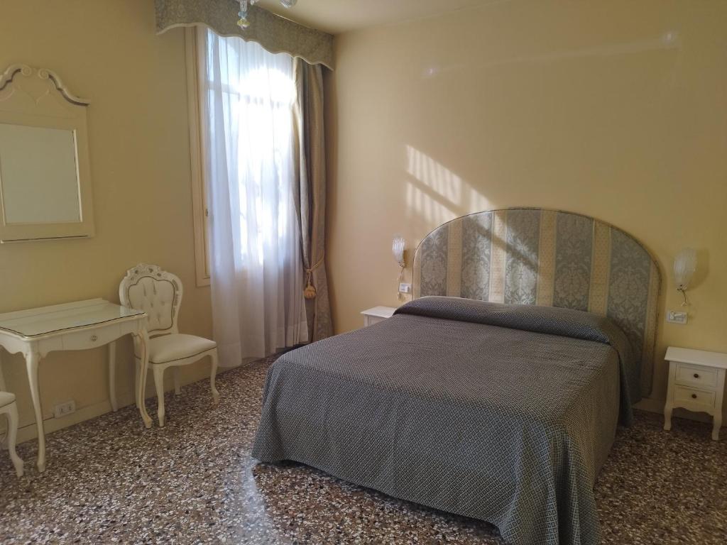 a bedroom with a bed and a desk and a window at Alloggi Acquavita - checkin at "Alloggi SS Giovanni e Paolo" in Venice