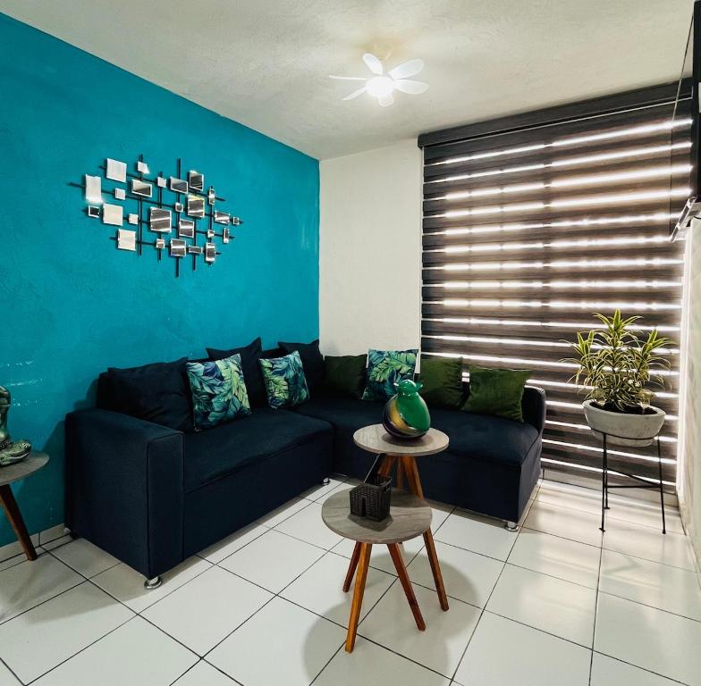 a living room with a black couch and a blue wall at Departamento a 10 minutos del aeropuerto in El Castillo