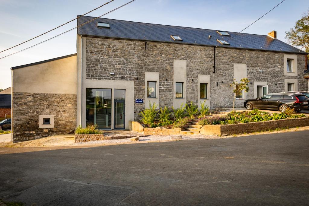 a brick building with a car parked in front of it at Le Petit Fief in Couvin