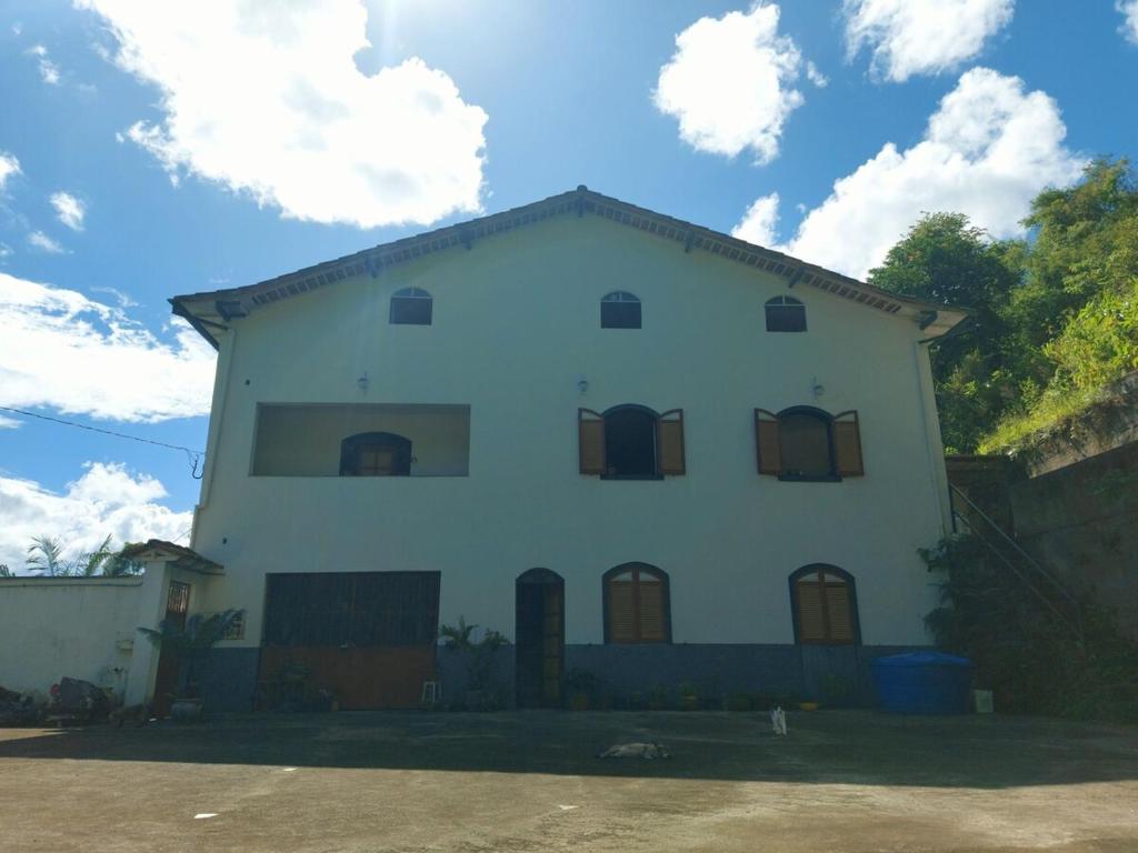a white house with brown windows and a sky at Casa Antiga em OP in Ouro Preto