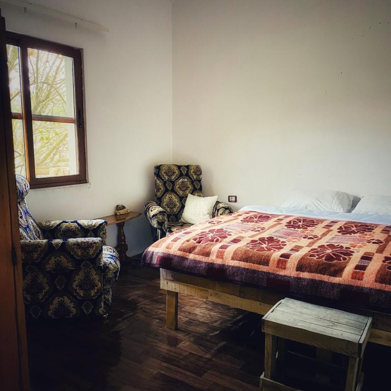 een slaapkamer met een bed en 2 stoelen en een raam bij Guesthouse RAMAJ in Perondi