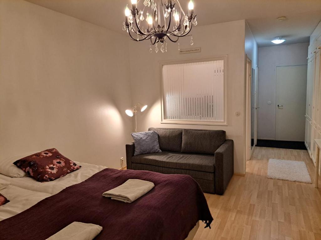 a bedroom with a bed and a couch and a chandelier at Studio Napa in Rovaniemi