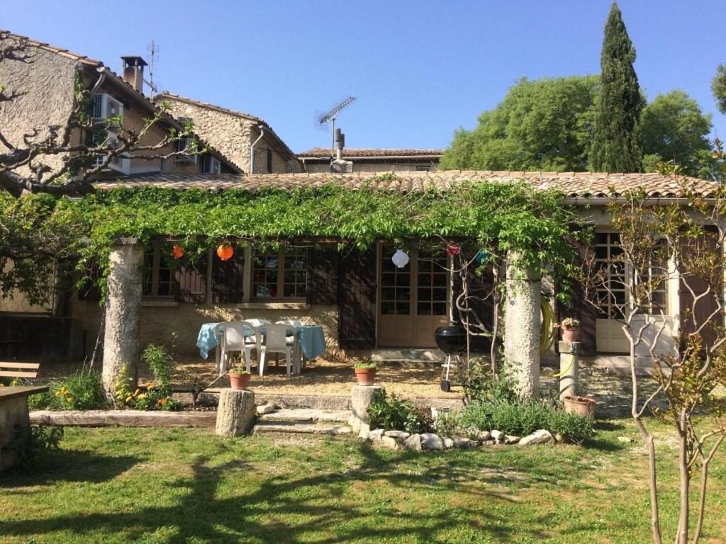 une maison avec une pergola et une table dans la cour dans l'établissement Gite du Relarguier, maison de village en Luberon, Provence, à Mérindol