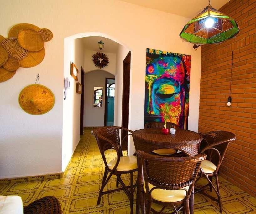 a dining room with a table and chairs and a painting at Casa aconchegante na praia in Peruíbe