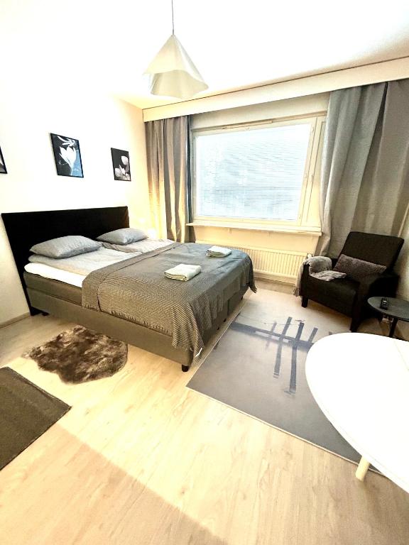 a bedroom with a bed and a chair and a window at Yksiö Jyväskylässä Savela in Jyväskylä