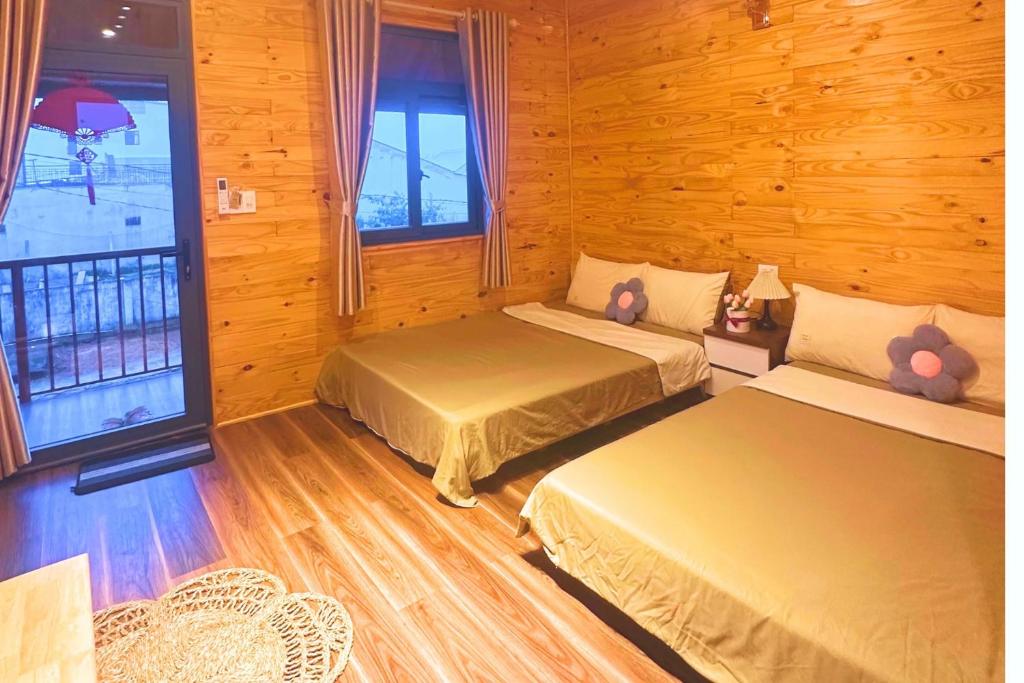 a bedroom with two beds and a balcony at T'Gins Măng Đen Homestay in Kon Plong