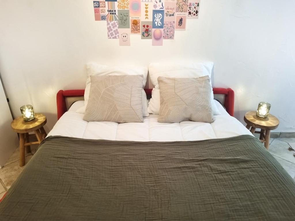 ein Bett mit weißen Laken und Kissen und Bildern an der Wand in der Unterkunft Studio cosy à 200m de la plage Parking & Wi-Fi in Bormes-les-Mimosas