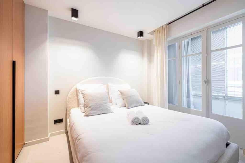 une chambre avec un grand lit blanc avec une fenêtre dans l'établissement Pasteur Luxury apartment la Croisette, à Cannes
