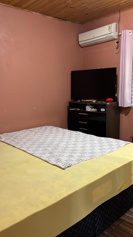 a bedroom with a bed and a flat screen tv at Casa Ana in São Gabriel