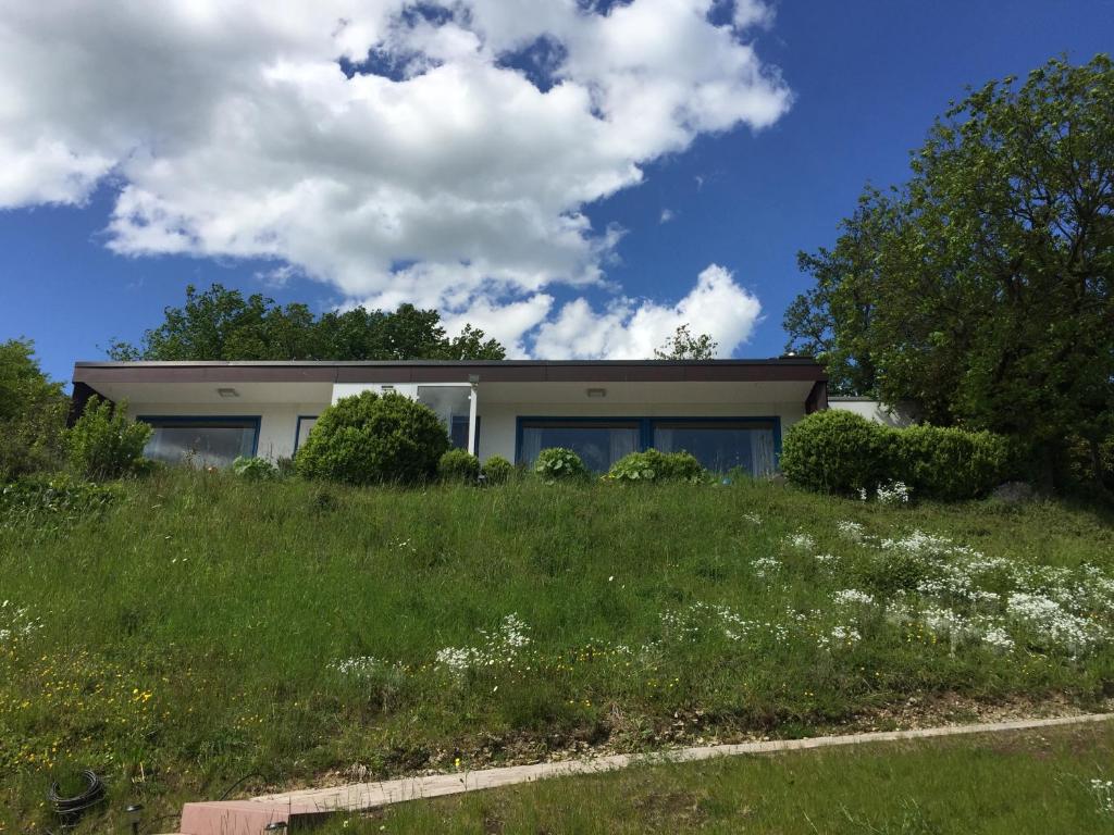 une maison au sommet d'une colline herbeuse dans l'établissement Idyllisch Wohnen im Weserbergland - Bungalow mit phantastischer Aussicht für 4 Personen, à Polle