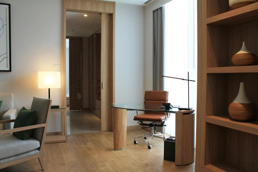 A room-side work nook with a glass desk, rolling chair and built-in display shelving.