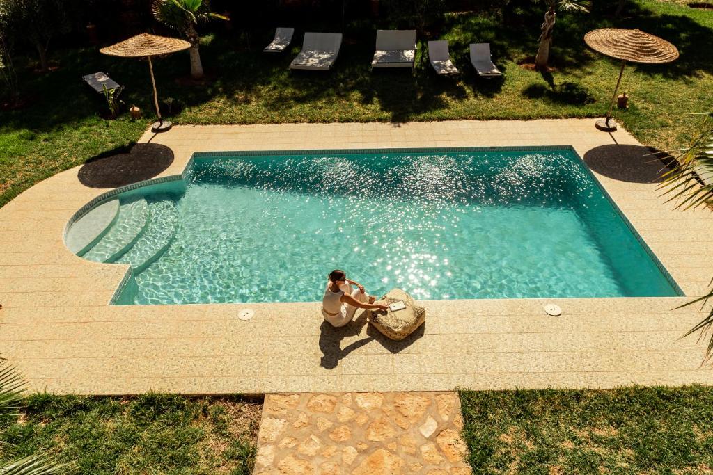 a man and woman sitting in a swimming pool at La Vida Surf - Yoga Villa in Ounara