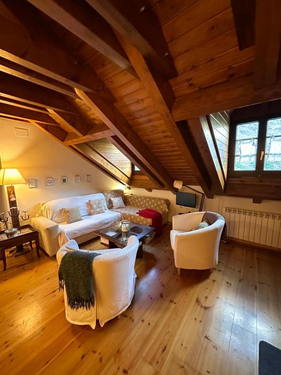 a large living room with white furniture and wooden ceilings at Lo somni del riu in Llavorsí