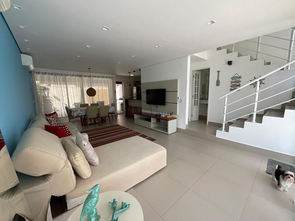 a living room with a white couch and a television at Casa Pé na Areia Boiçucanga in São Sebastião