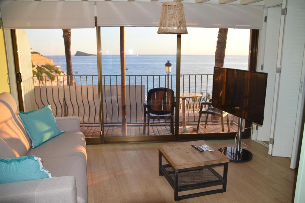 a living room with a couch and a tv and the ocean at Apartamentos Playa Pequeña in Benidorm