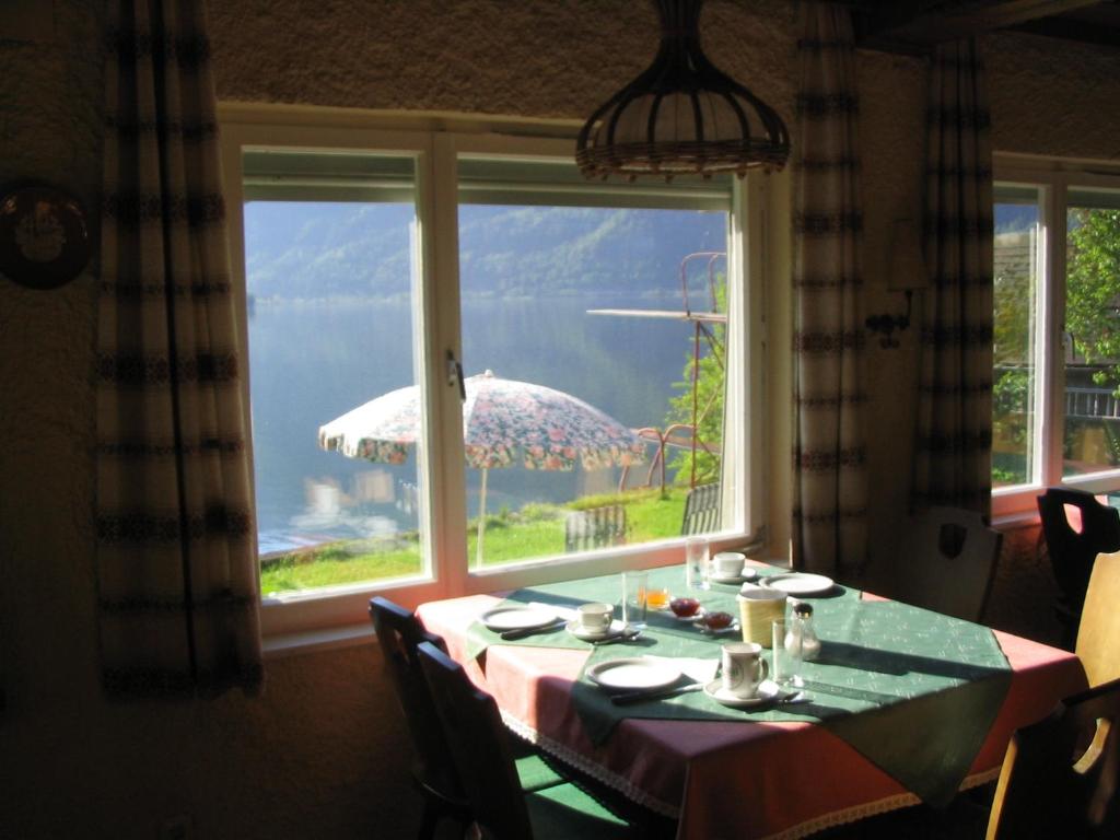 a table with an umbrella in a room with a window at Pension Sarstein in Hallstatt
