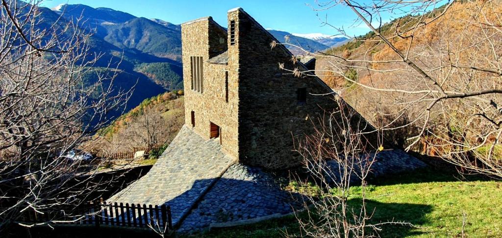 a building on a hill with mountains in the background at Cal Brugués - Casa de montanya in Ribes de Freser