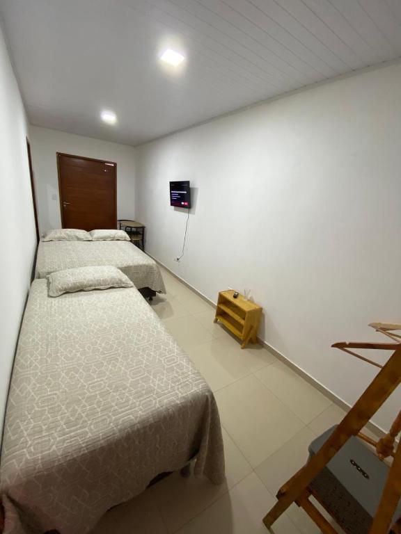 Un dormitorio con dos camas y un televisor en la pared. en Recando Dourado Suíte 4, en São Miguel dos Milagres