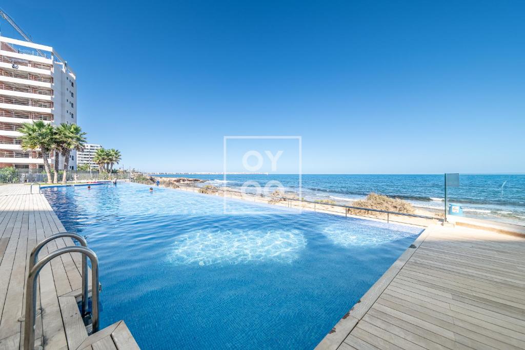 - une piscine à côté d'une plage donnant sur l'océan dans l'établissement Infinity Blue Luxury Flat by OYOOSTAYS, à Torrevieja