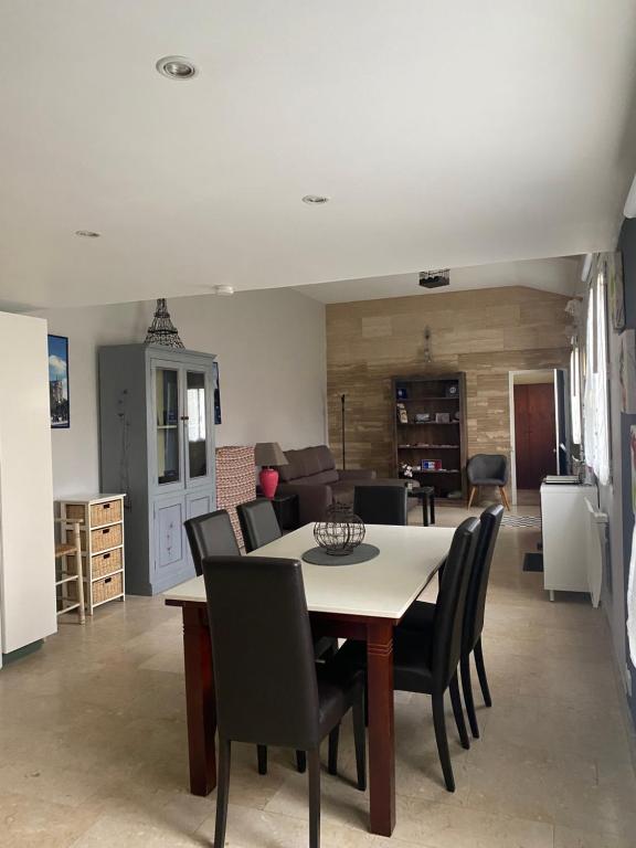 a dining room and living room with a table and chairs at L'Araucaria in Pontault-Combault