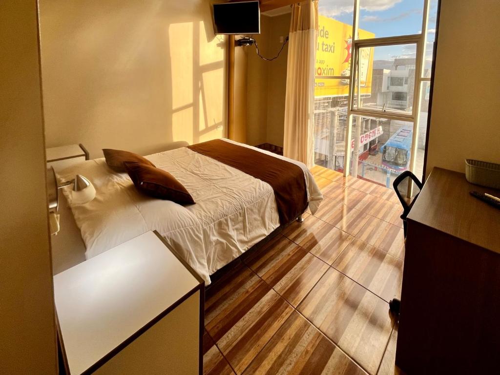 Un dormitorio con una cama y una ventana grande. en EmbajadaWanka, en Huancayo