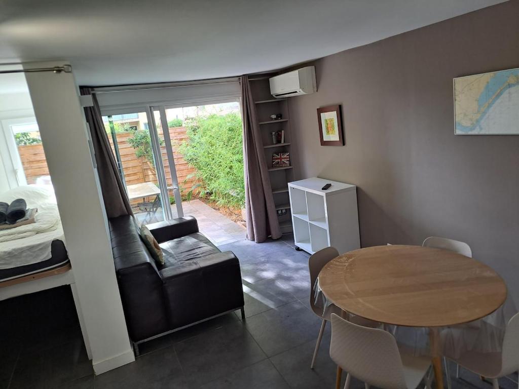 Zimmer mit einem Tisch und einem Bett sowie einem Tisch und Stühlen in der Unterkunft Hameau du Puech, rez-de-jardin avec parking et clim in Cap d'Agde
