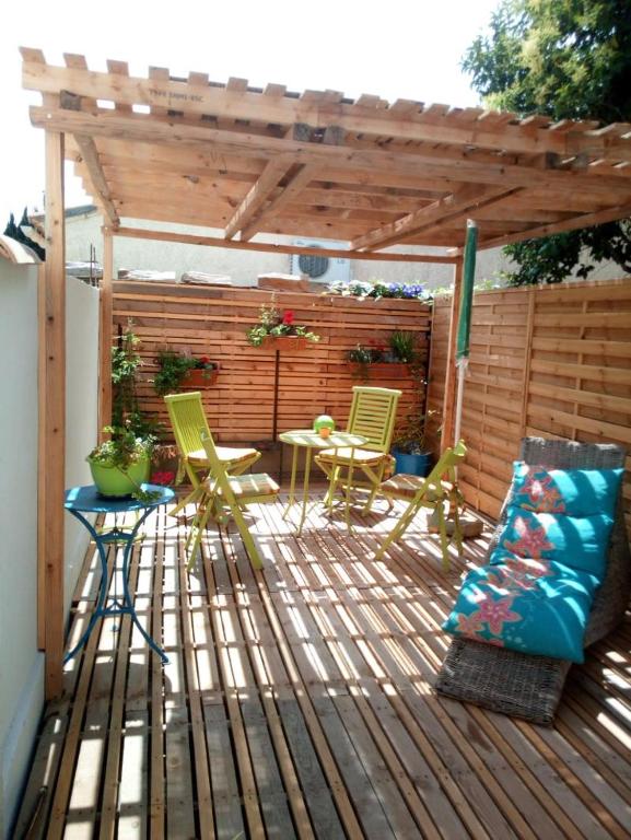 une terrasse en bois avec des chaises, une table et une pergola dans l'établissement Studio plien pied avec terrasse ensoleillée, à Leucate