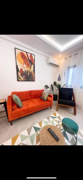 - un salon avec un canapé orange et une chaise dans l'établissement Le charme de Issy, à Issy-les-Moulineaux