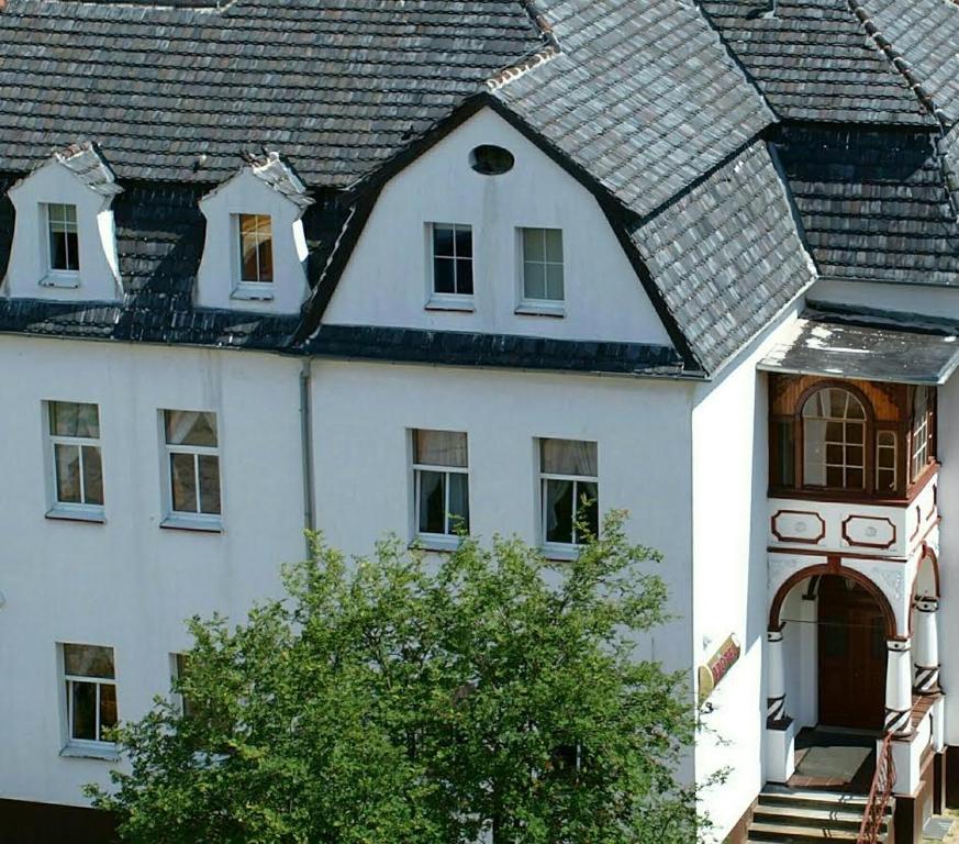 een wit huis met een grijs dak bij Hotel Okatex in Żagań