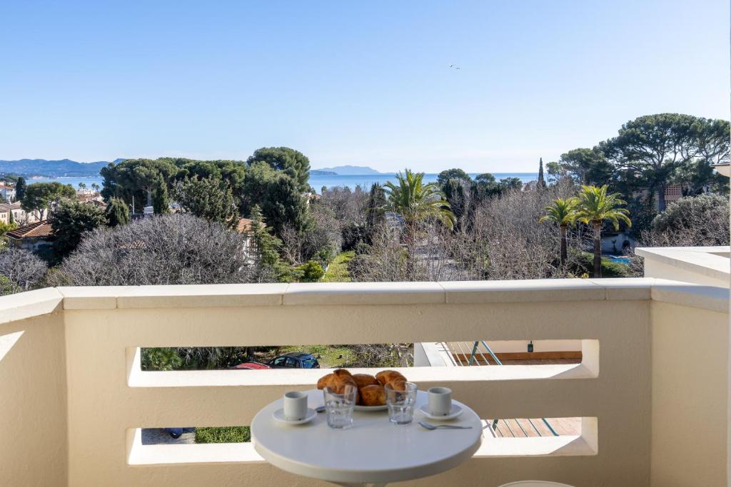 - une table blanche sur un balcon avec vue sur les arbres dans l'établissement Appartement T2 avec Vue Mer au Palais Lumière, à La Ciotat