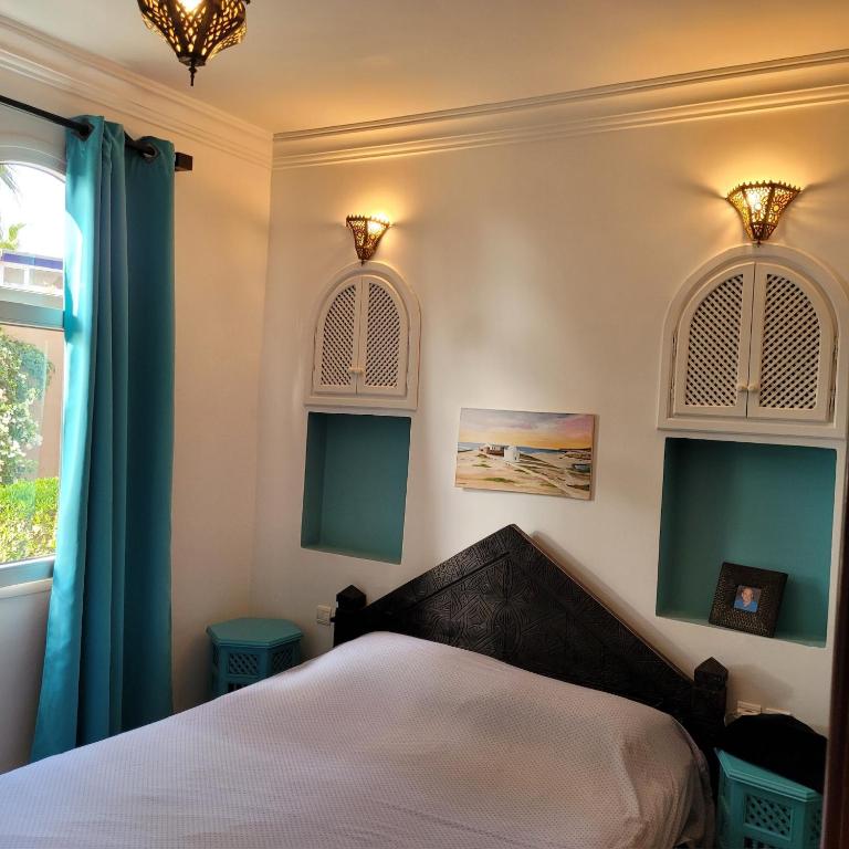 a bedroom with a bed with blue curtains and a window at Villa du soleil in Mirleft