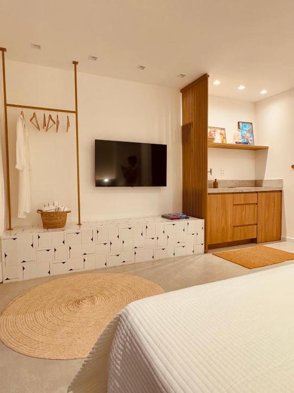 萨尔瓦多IorubaStudio的卧室配有白色瓷砖墙壁上的电视