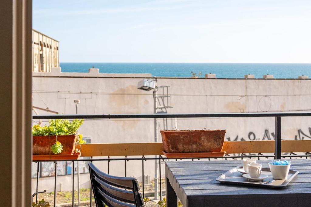 a table on a balcony with a view of the ocean at Casa Nina Quadrilocale Top a 50m dal Mare in Pietra Ligure