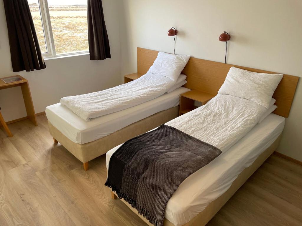 two twin beds in a room with a window at Lambastadir Guesthouse in Selfoss