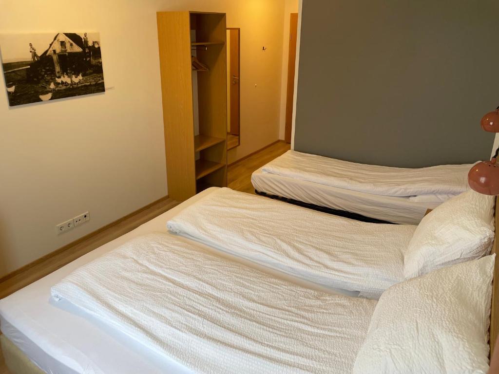 two beds in a room with white sheets at Lambastadir Guesthouse in Selfoss