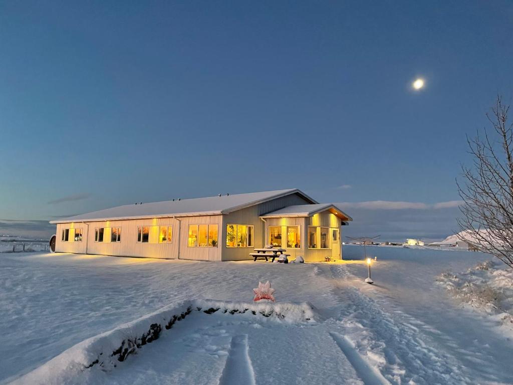 a house in the snow with lights on at Lambastadir Guesthouse in Selfoss