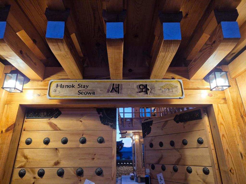 ein Holzgebäude mit einem Schild an der Decke in der Unterkunft Hanok Stay Seowa in Gyeongju