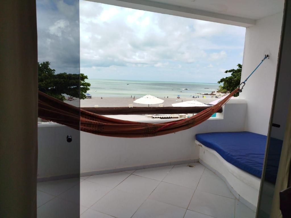 a hammock in a room with a view of a beach at Habana Flats Praia in Natal