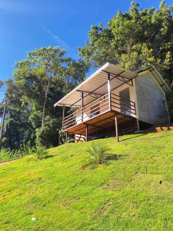 a house on top of a grassy hill at Chalé Roda Dágua B in Alto Caparao