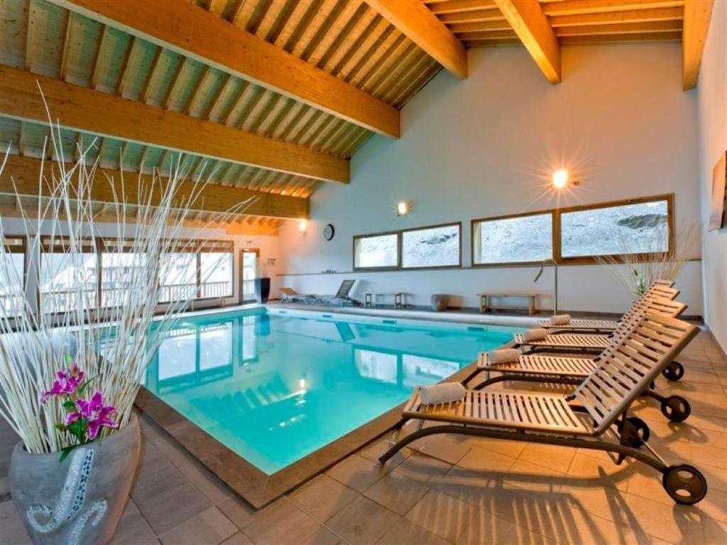 - une piscine avec 2 chaises longues dans une maison dans l'établissement Apartment in Orelle near Ski Lift 3 Vallées, à Orelle