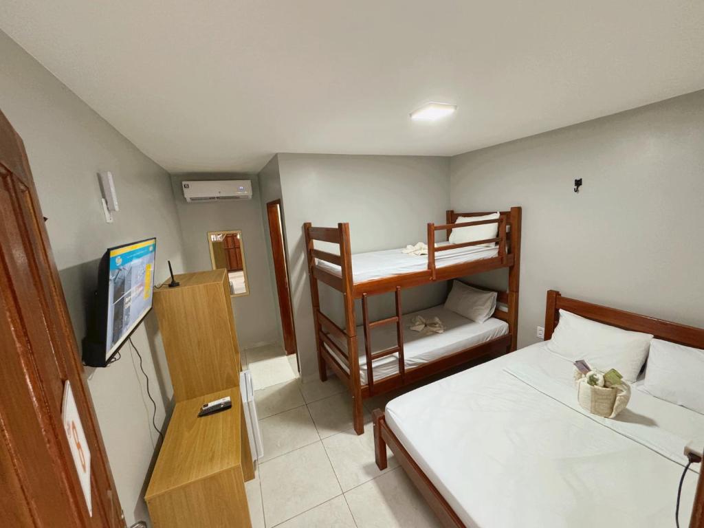 a small room with two bunk beds and a television at Hotel Calleb in Presidente Figueiredo