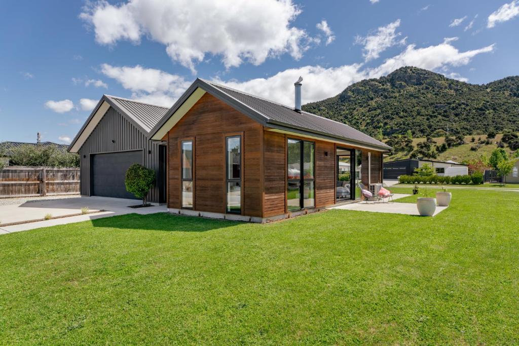 a house with a large yard with green grass at The Alpine Patch - Wanaka Holiday Home in Wanaka