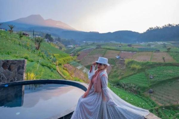 a woman in a dress and hat standing on a ledge at Villa The Noman Tawangmangu by Suasana Villa in Sarangan