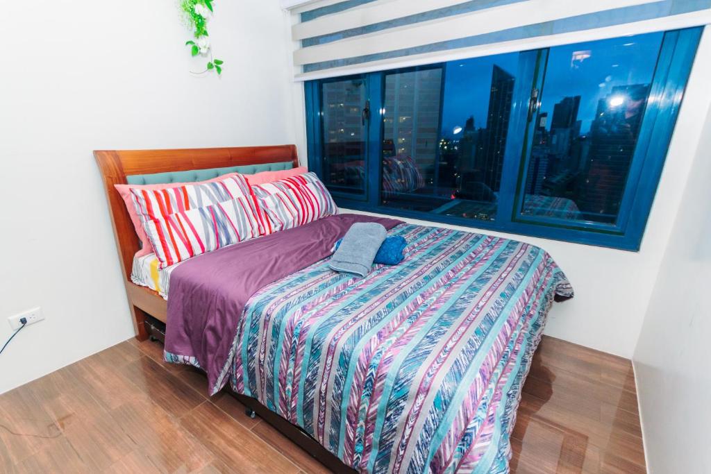 a bedroom with a bed and a window with a city skyline at Urban Charm Cozy Meet 52 Air Swim Gym Park 300Mb in Manila