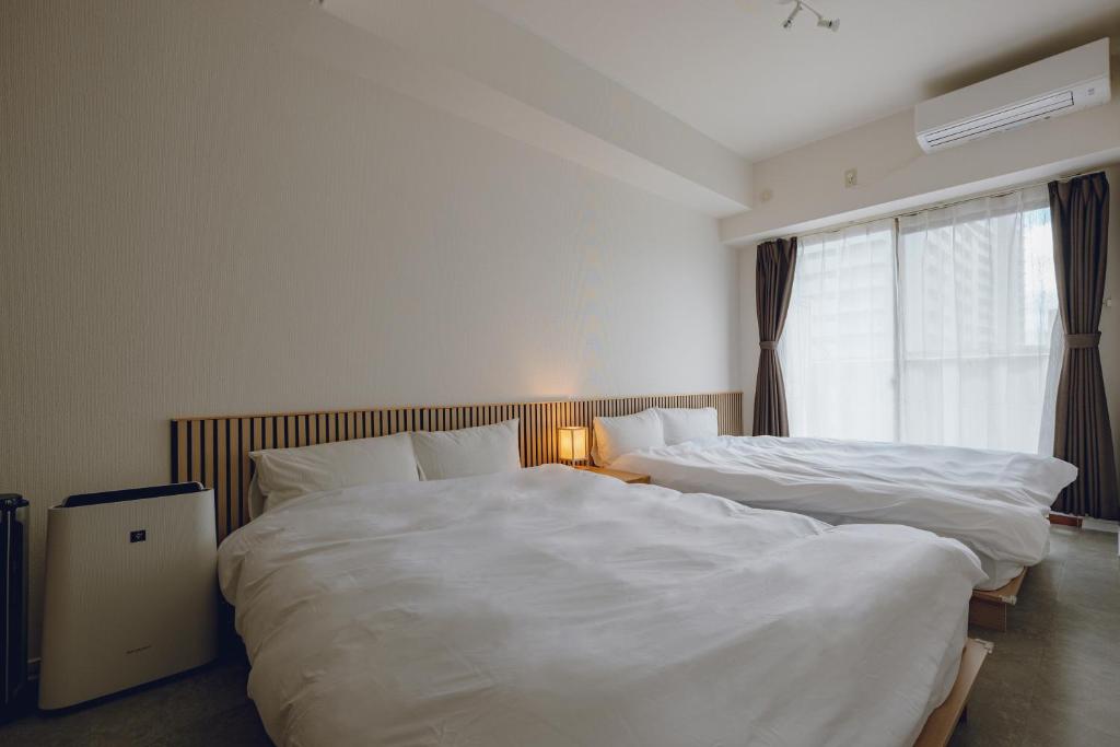 two beds in a hotel room with white sheets at Coda House in Aoichō