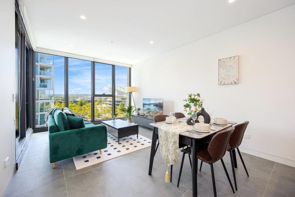a living room with a table and a green couch at Lidcombe Apt Near Olympic Park Train in Sydney
